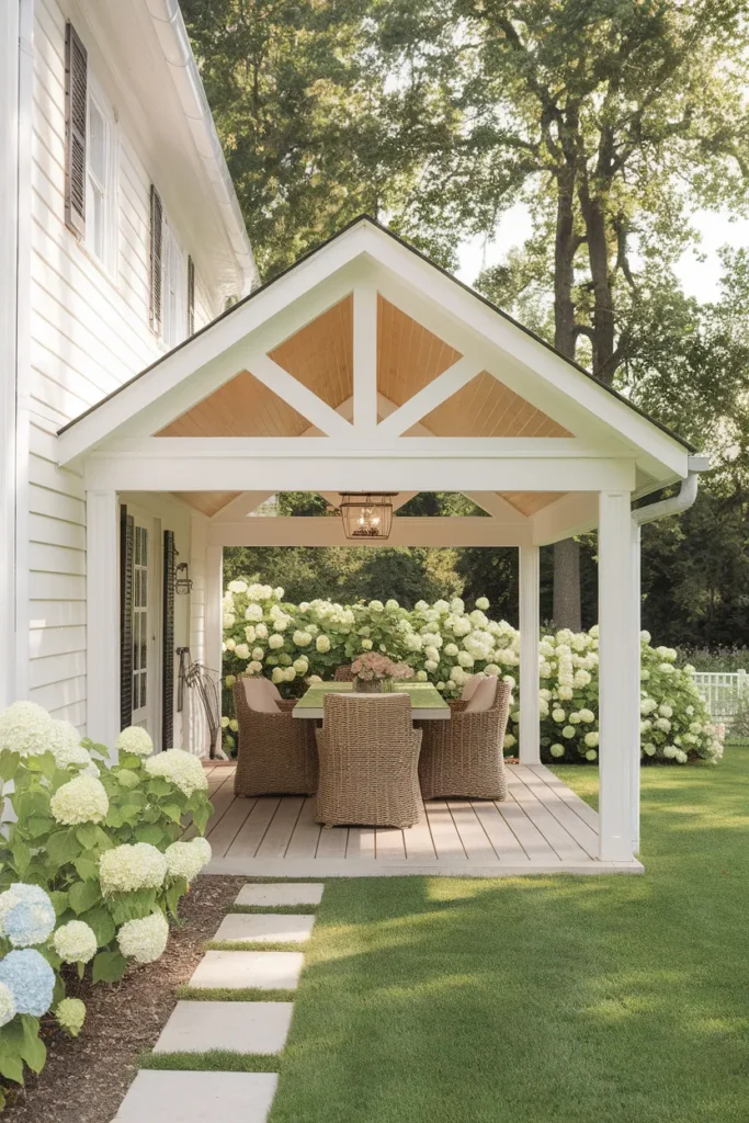 Patio roof ideas white gable roof extension shading a farmhouse dining patio in bright midday sun