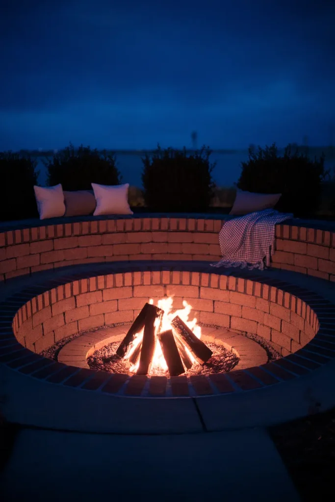 Sunken brick fire pit with brick step seating glowing at blue hour