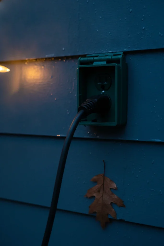 Outdoor rated cord plugged into a weatherproof GFCI outlet cover for backyard lighting