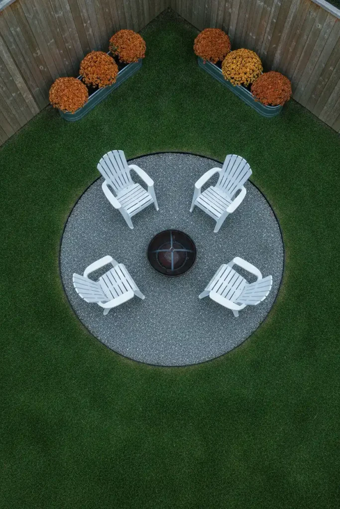 Overhead view of a gravel corner fire pit area cut into lawn with steel edging and mums