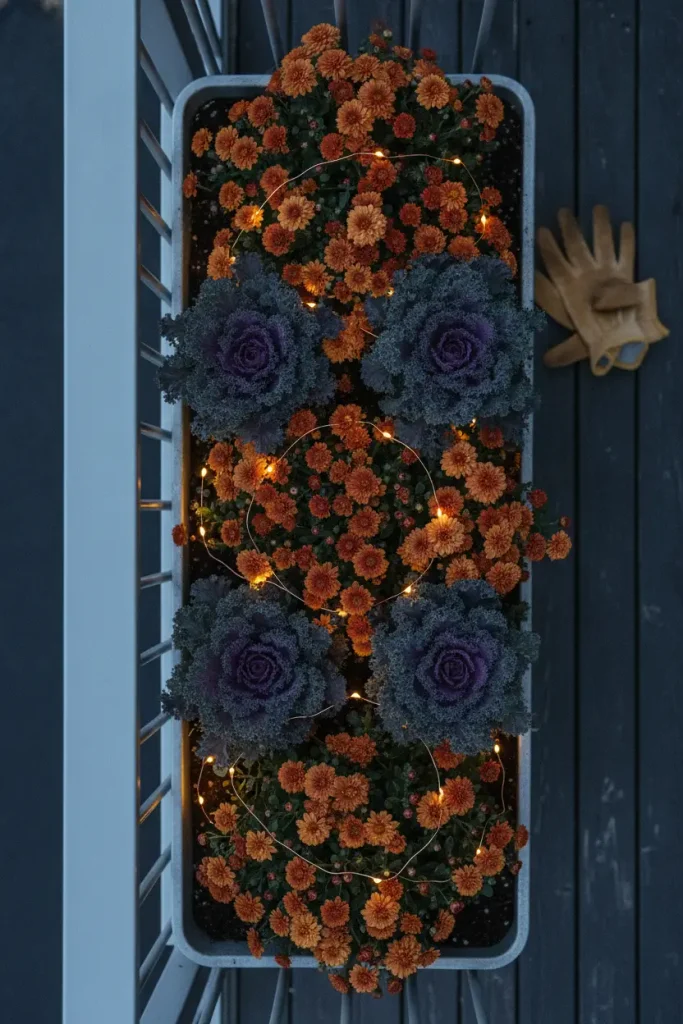 Rail planter of mums with fairy lights, a fall balcony decor lighting idea for apartments