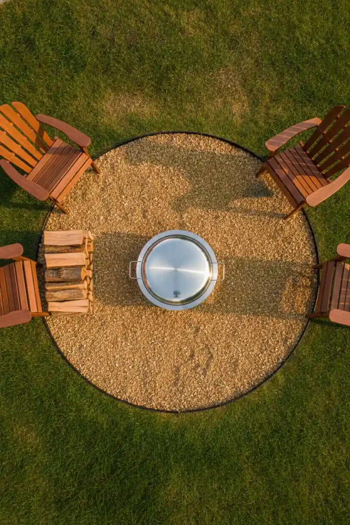 Rustic cozy backyard fire pit on a pea gravel circle with steel edging, seen from above