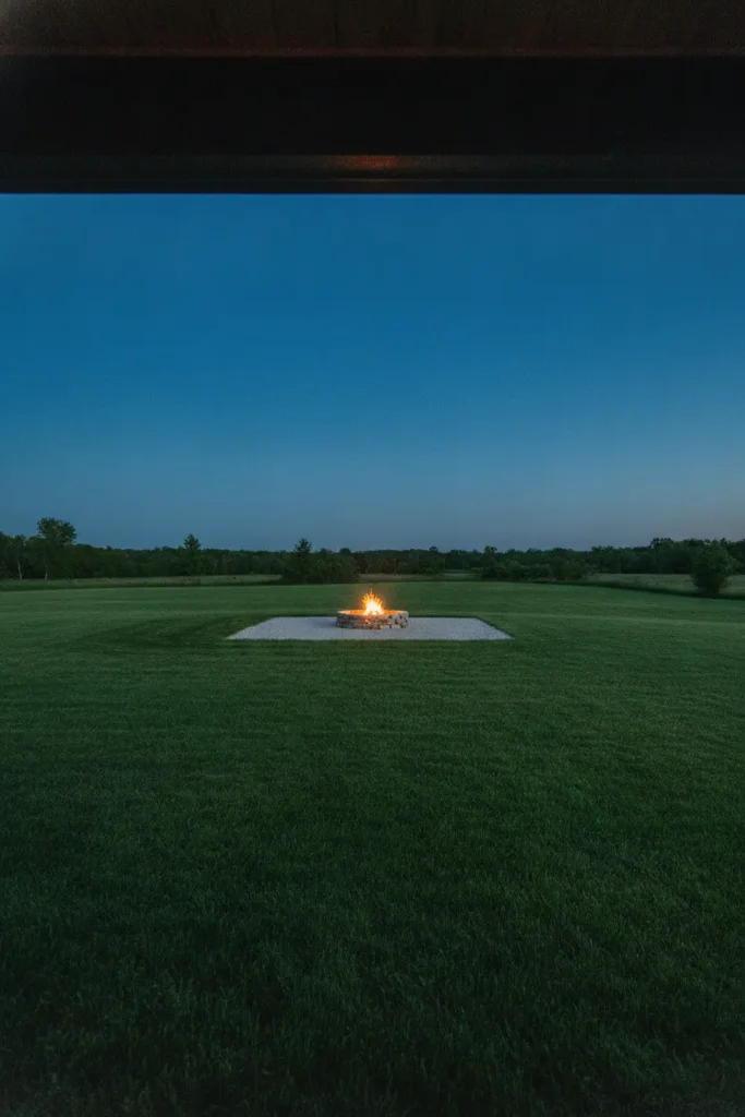 View from a back porch to a rustic fire pit set well out in the yard, clear of the house and trees